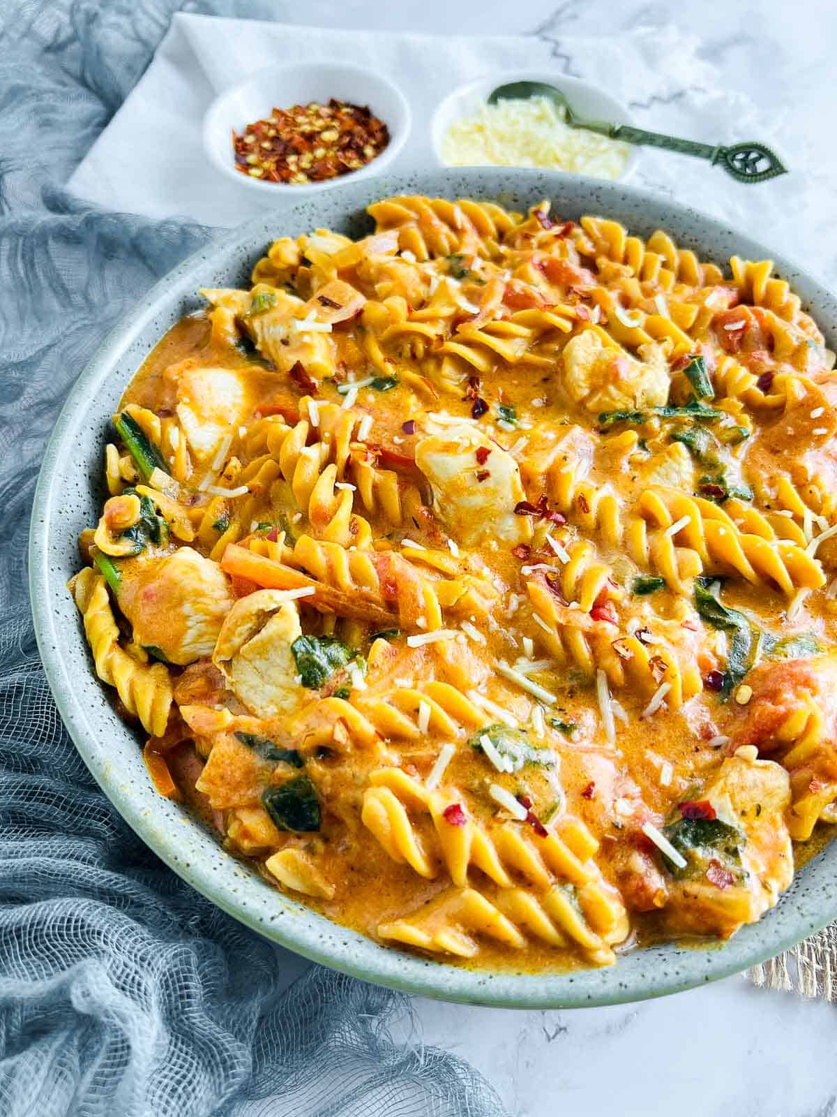 Chicken chickpea pasta close up with cheese in the background.