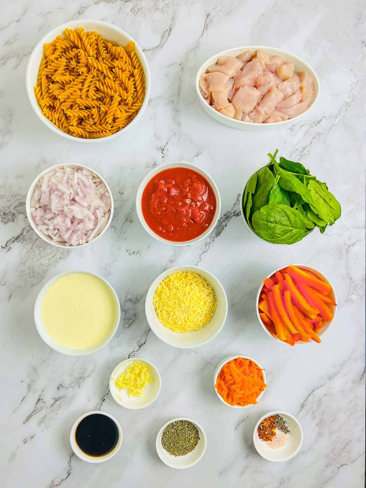 Ingredients to make chicken chickpea pasta on a marble surface.