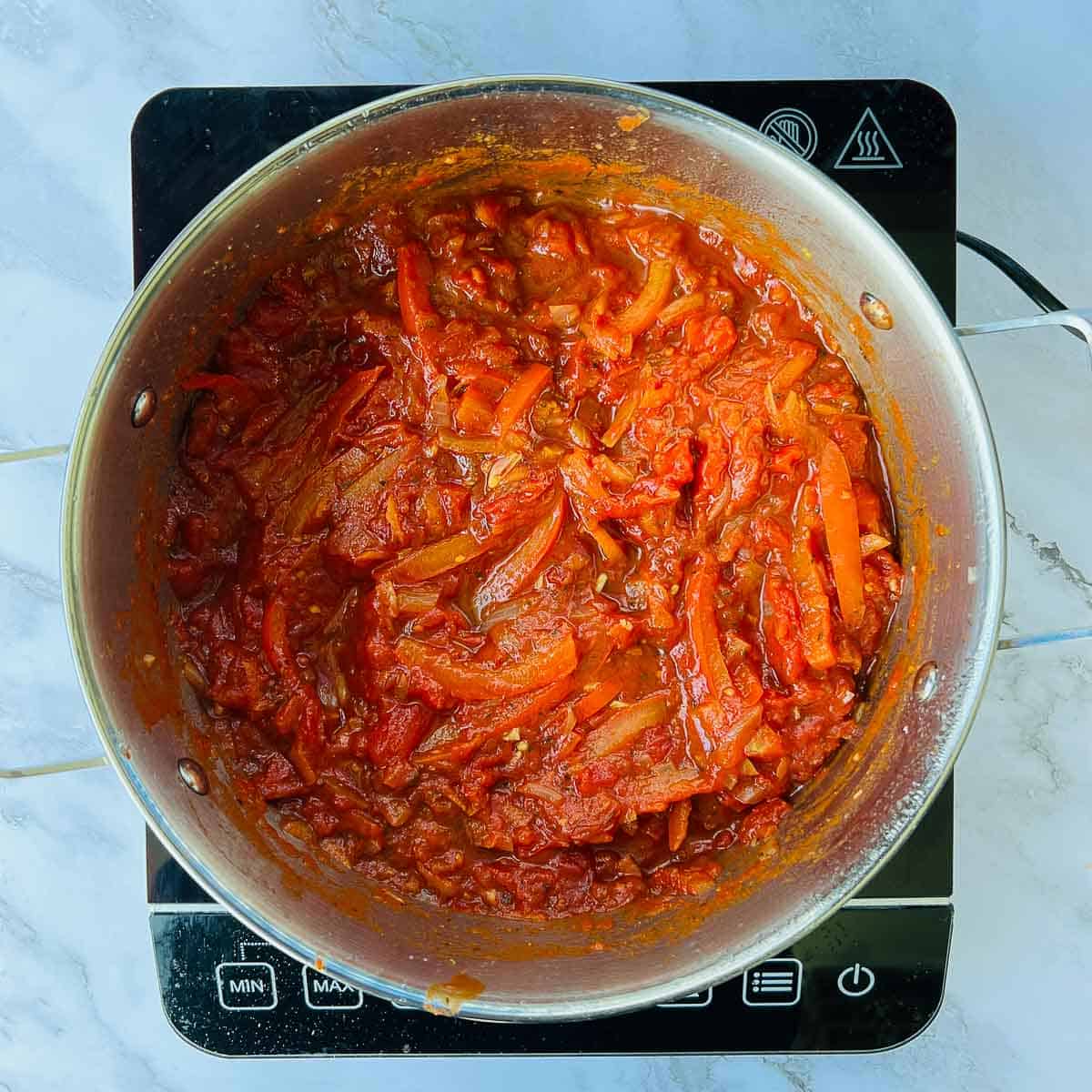 Onion, tomato, and veggie pasta sauce in the pot.