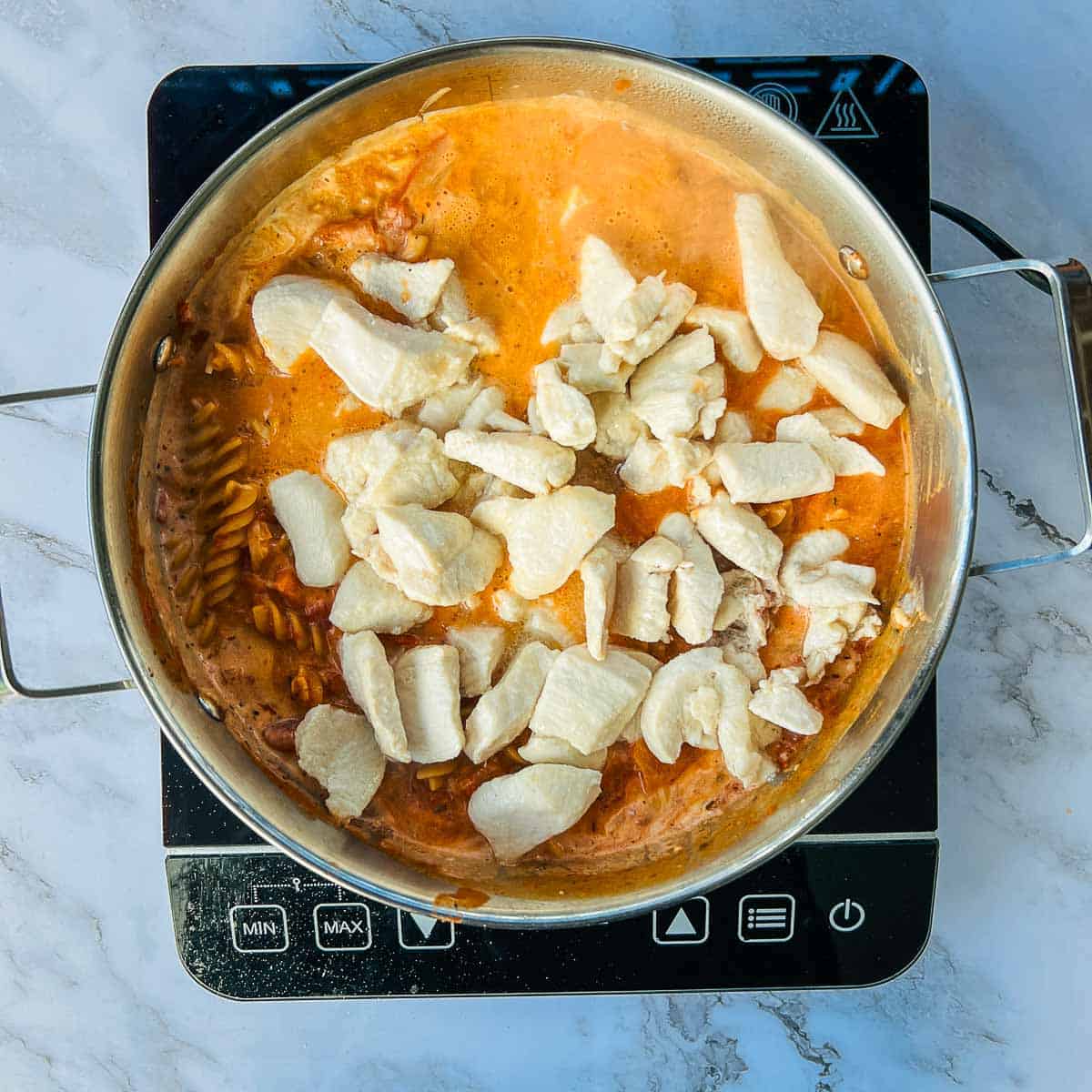 Cream, parmesan cheese, and brown chicken in the pot.