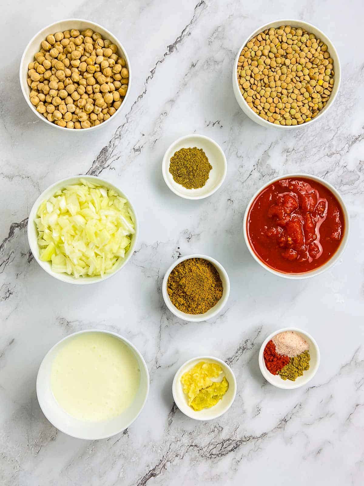 Ingredients to make chickpea lentil curry on a marble surface.