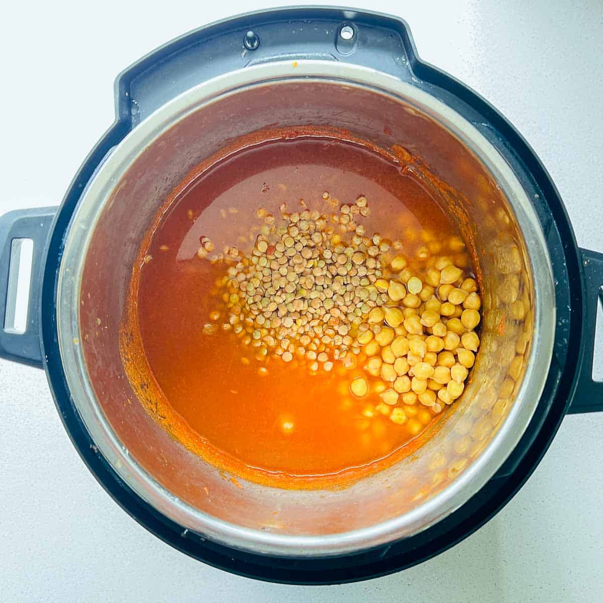 Chickpeas, lentil, and water added to Instant Pot before pressure cooking.