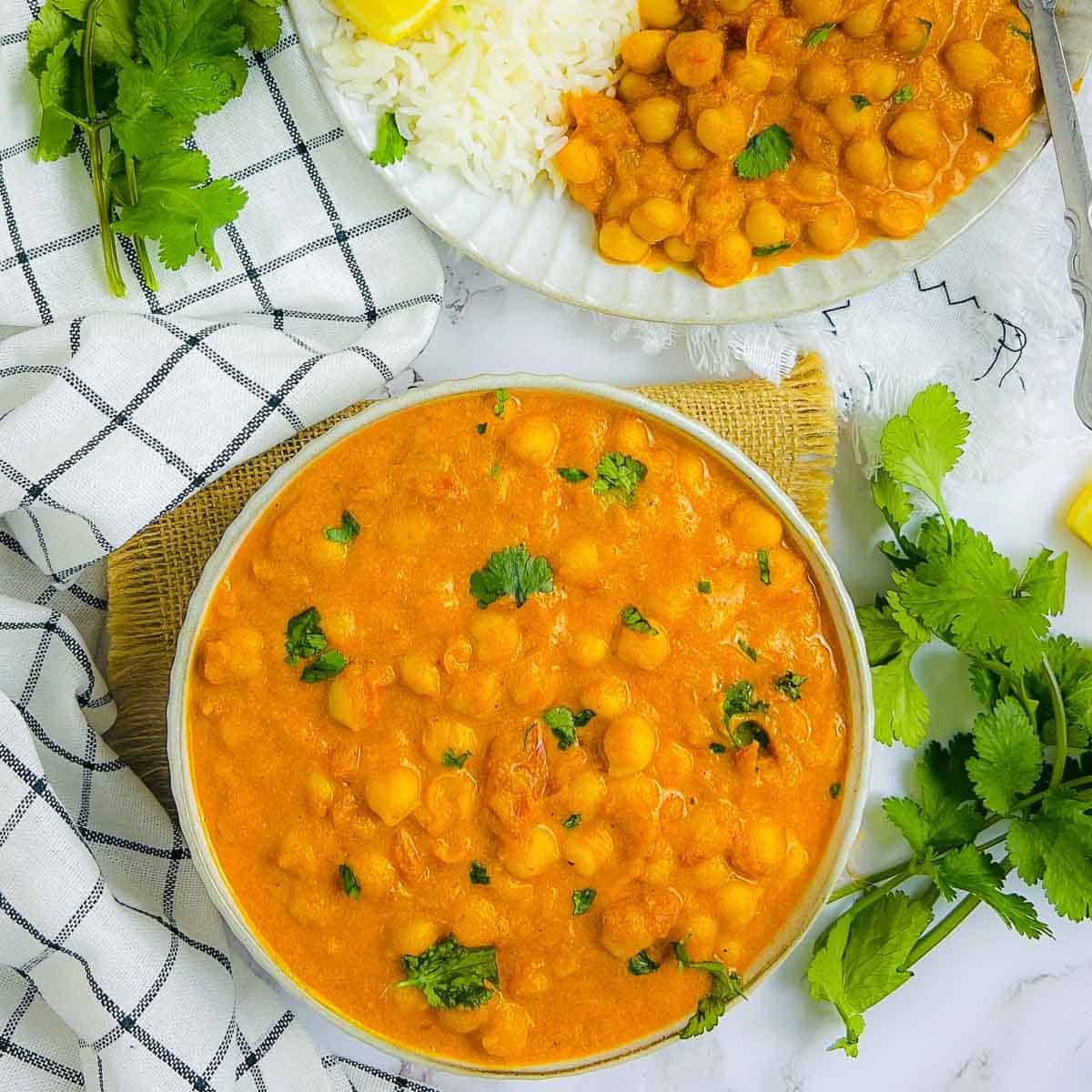 Chickpea mango curry in a white bowl with cilantro in the background.