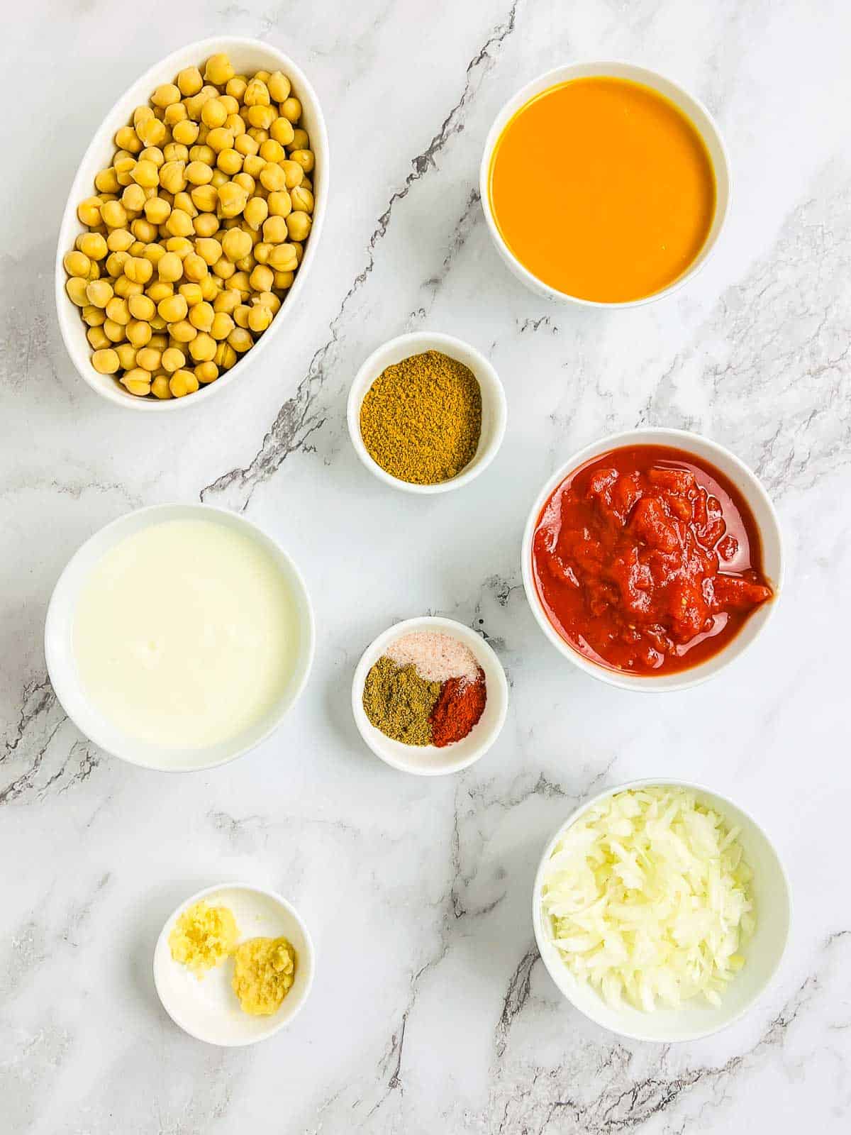 Ingredients to make chickpea mango curry on a marble surface.