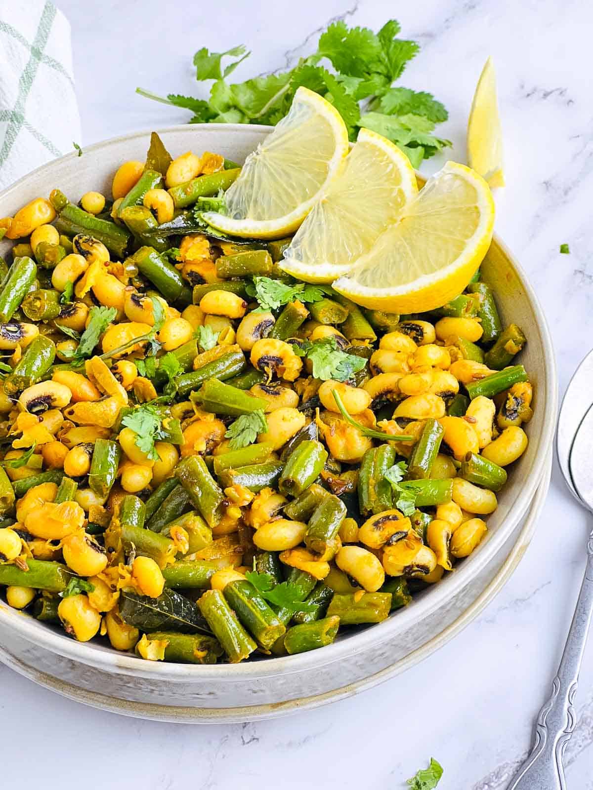 Green beans and black-eyed peas stir fry in a white bowl.