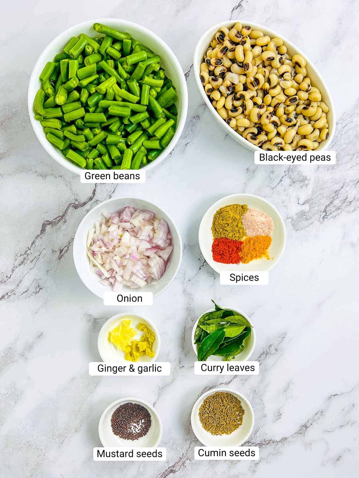 Ingredients to make green beans and black-eyed peas stir fry on a marble surface.