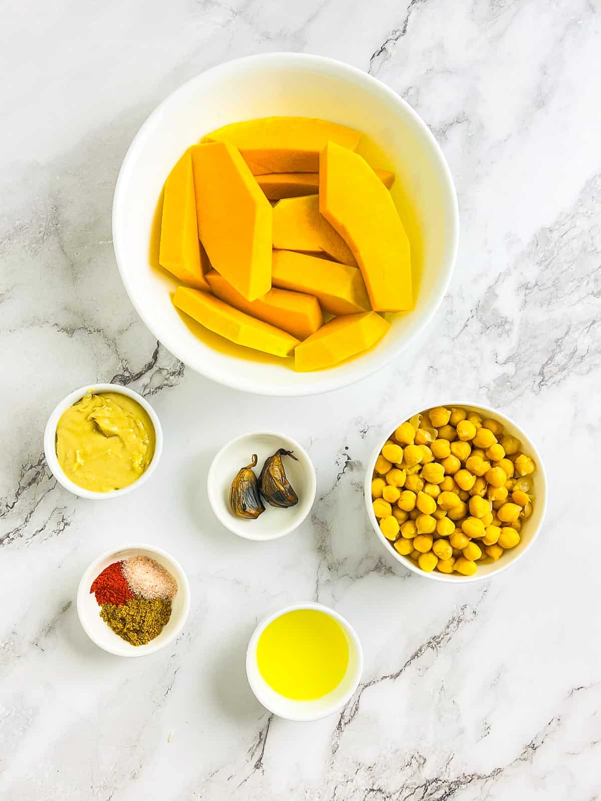 Ingredients to make pumpkin hummus on a marble surface.