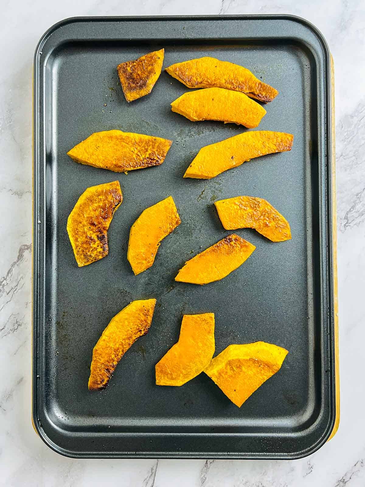 Oven roasted pumpkin on a baking tray.