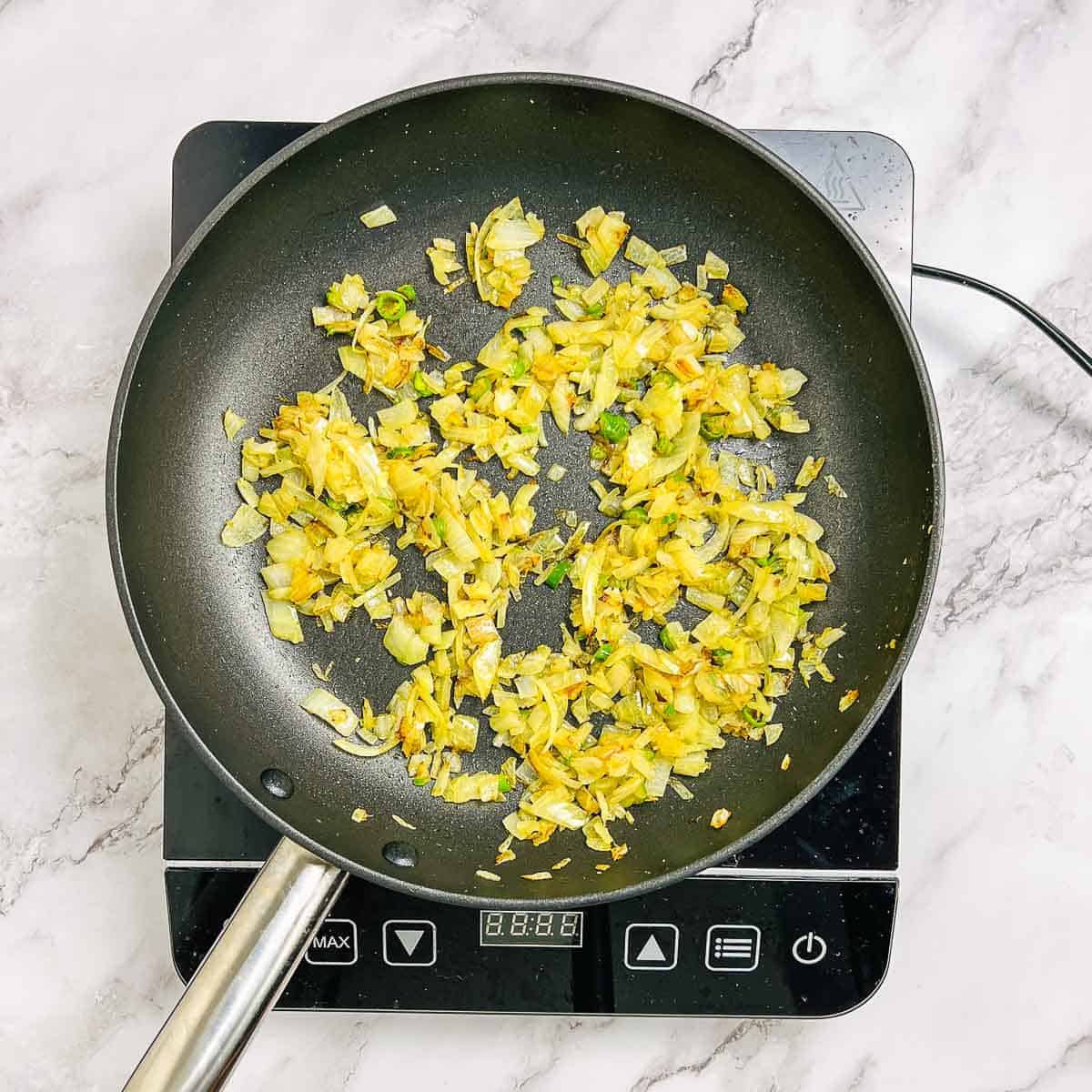 Sauteed onion, ginger, garlic,and chilies in a frying pan.