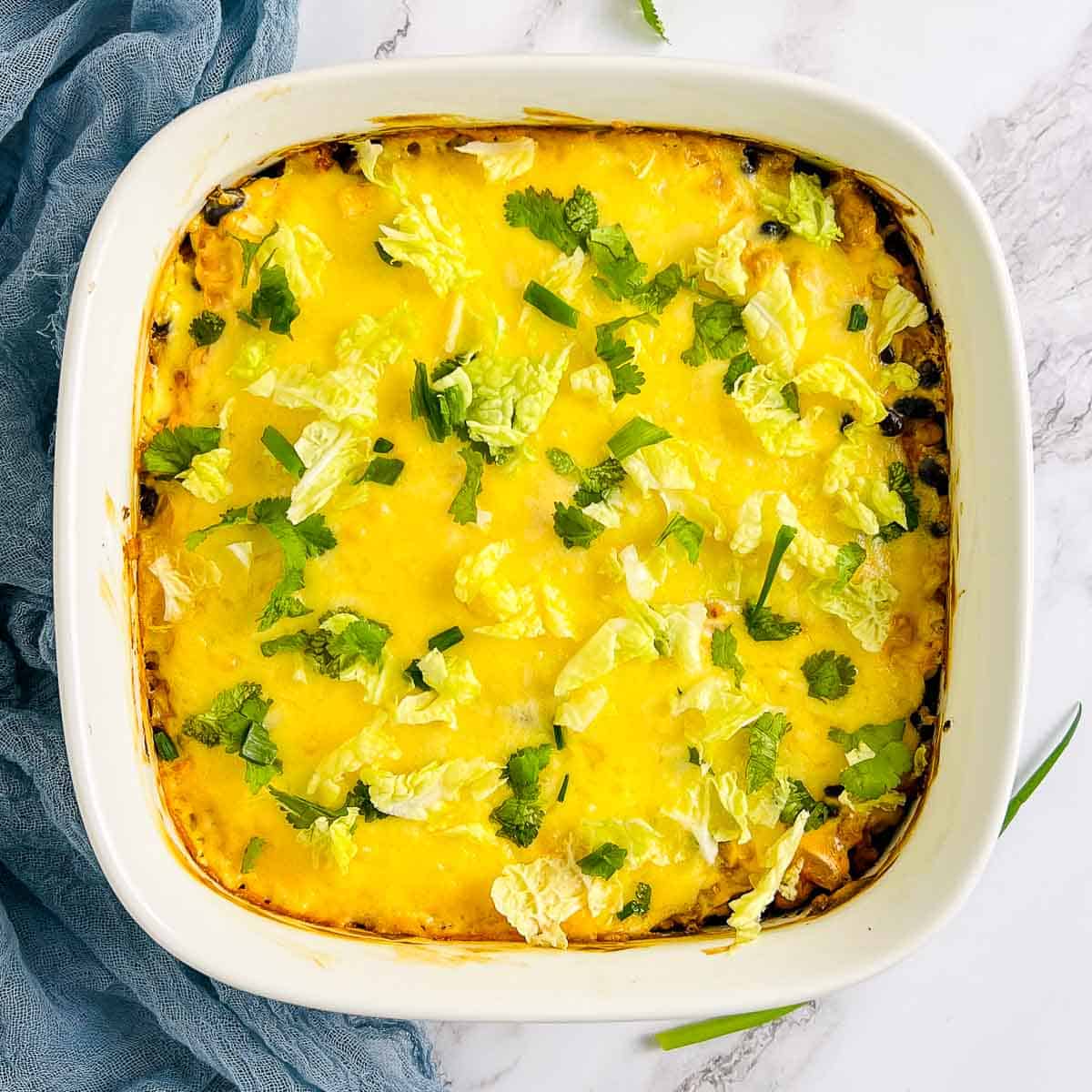 Walking taco casserole garnished with lettuce, scallions, and cilantro.