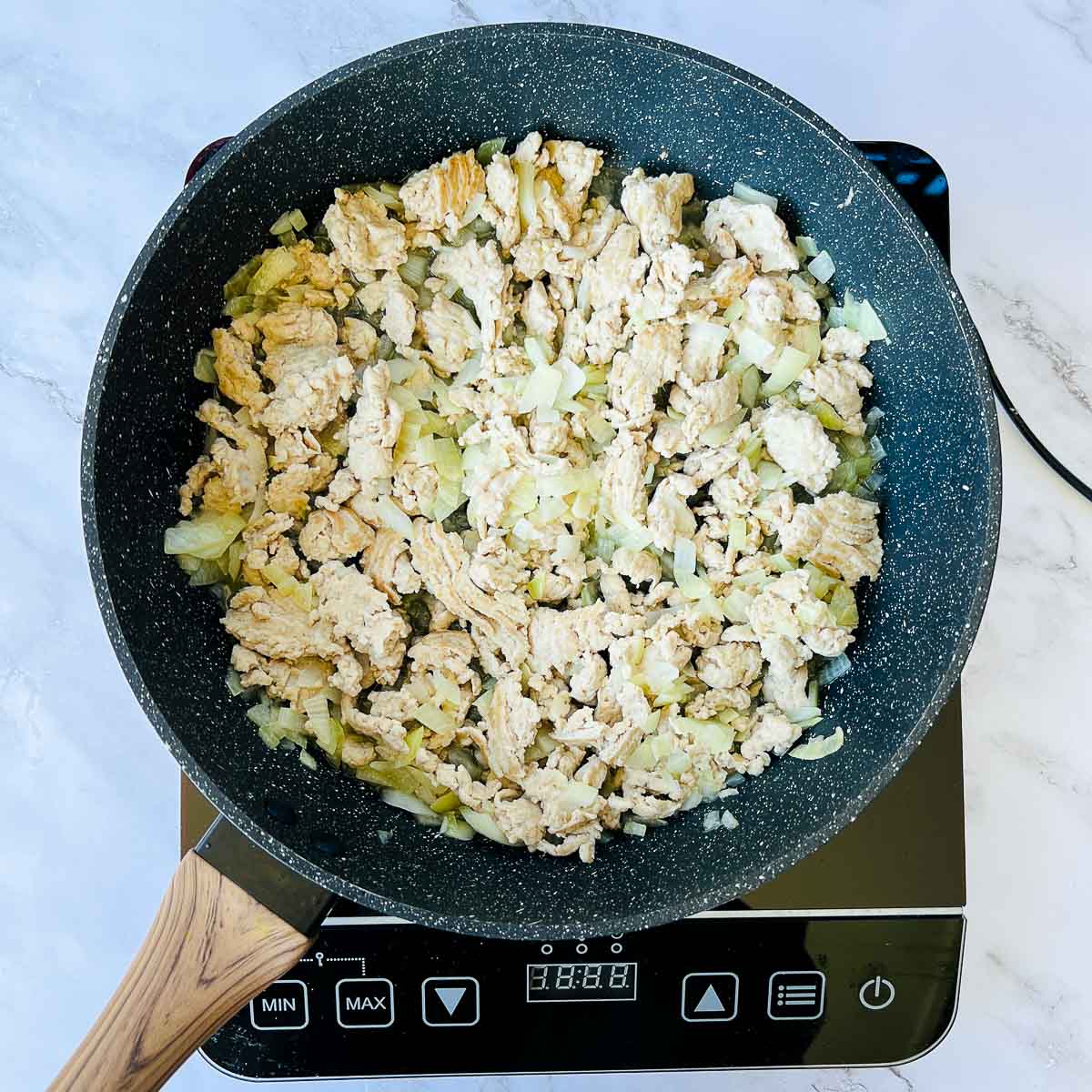 Sauted ground chicken and onions in a skillet.