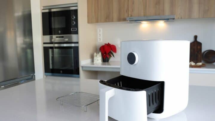 Air fryer on a kitchen counter with oven in the background.