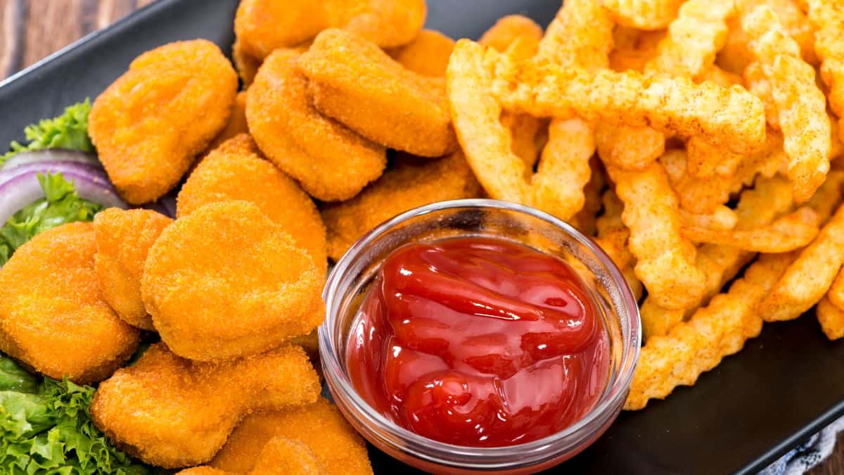 Chicken nuggets and fries on a black plate.