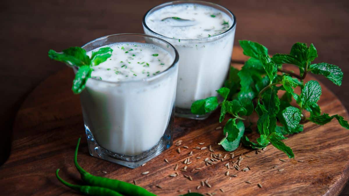 Two glasses of traditional buttermilk with mint leaves in the background.