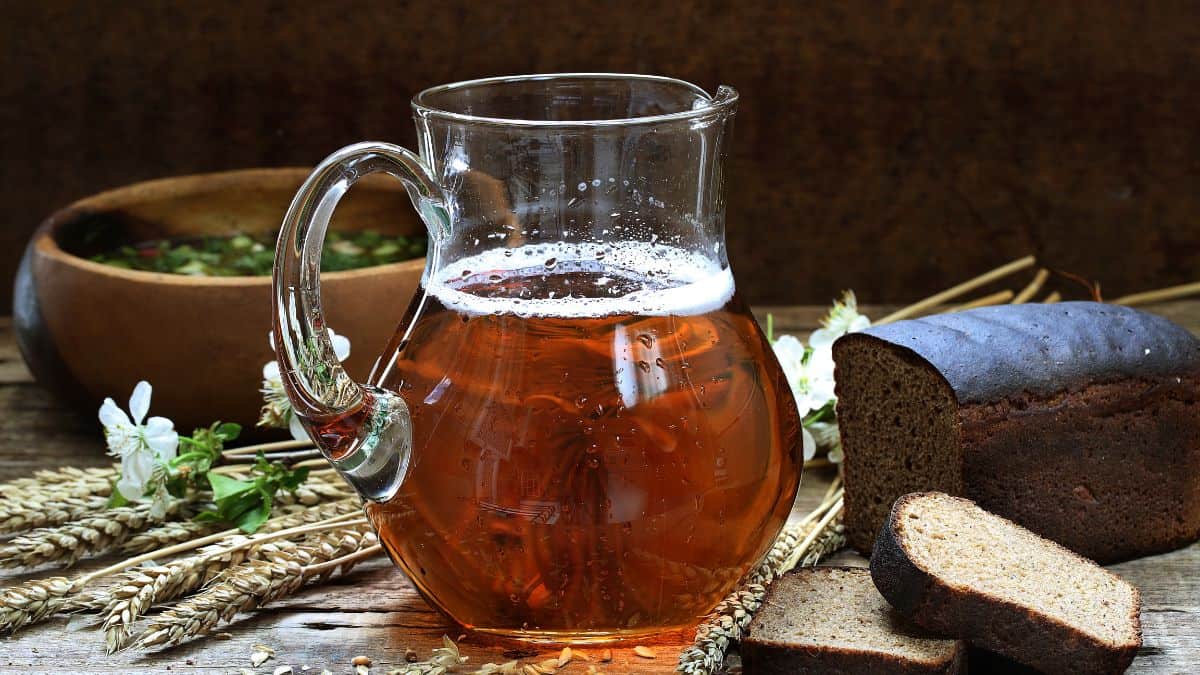 Kvass in a glaas jug with bread in the background.