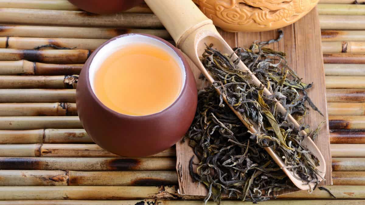 Oolong tea in a traditional cup with tea leaves in the background.