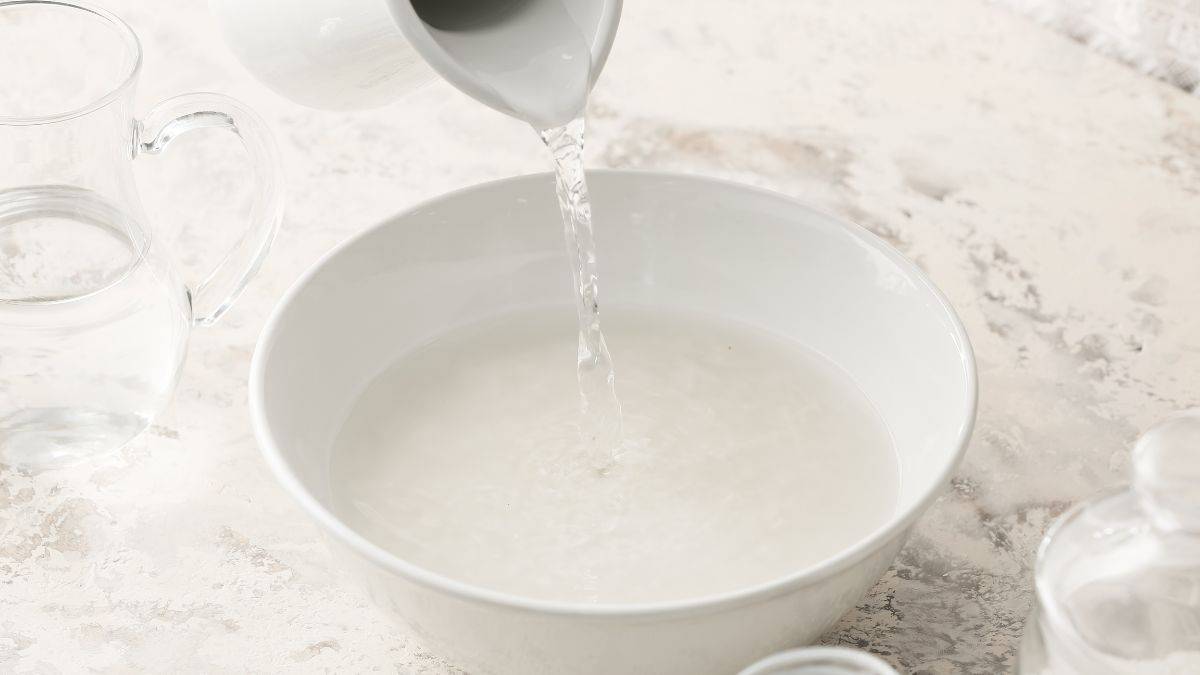 A bowl distilled vinegar on a wooden surface.