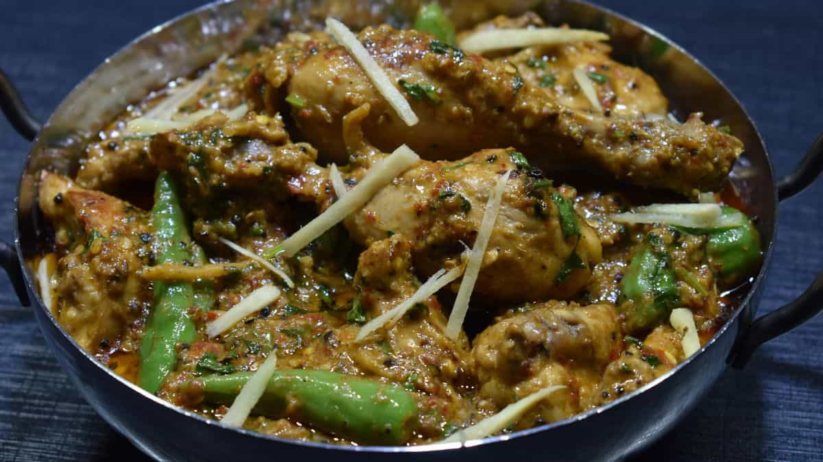 Chicken choila in a bowl garnished with ginger and green chili.