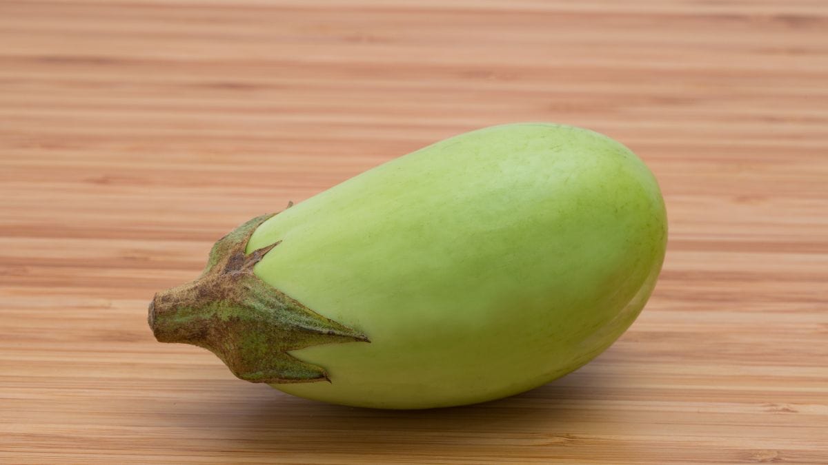 Green apple eggplant on a wooden surface.