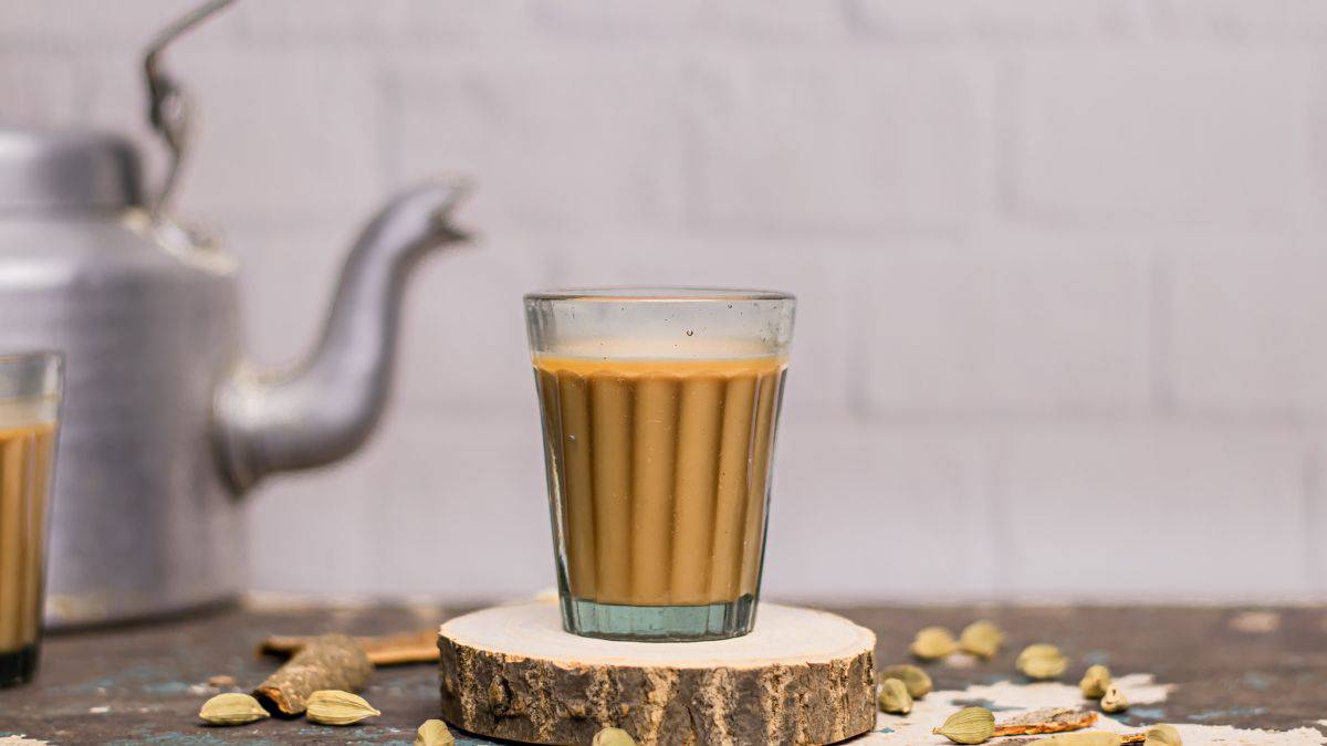 Masala chai in a cup with tea kettle in the background.