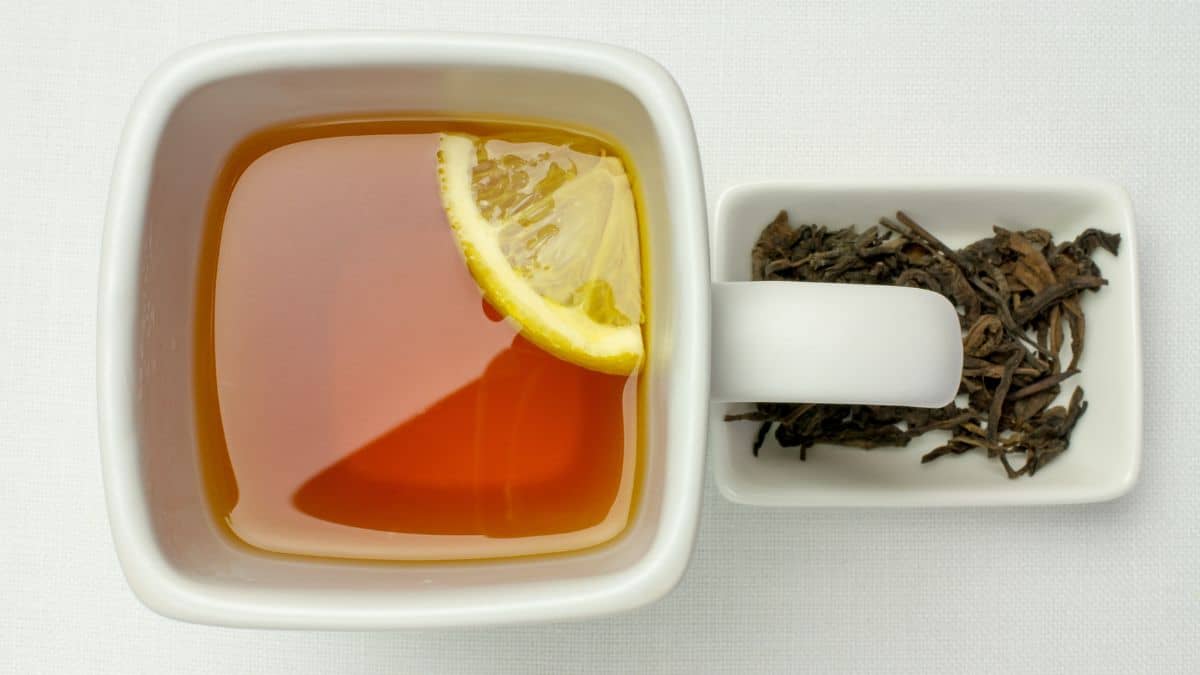 Russian tea topped with lemon slice and loose tea leaves in the background.