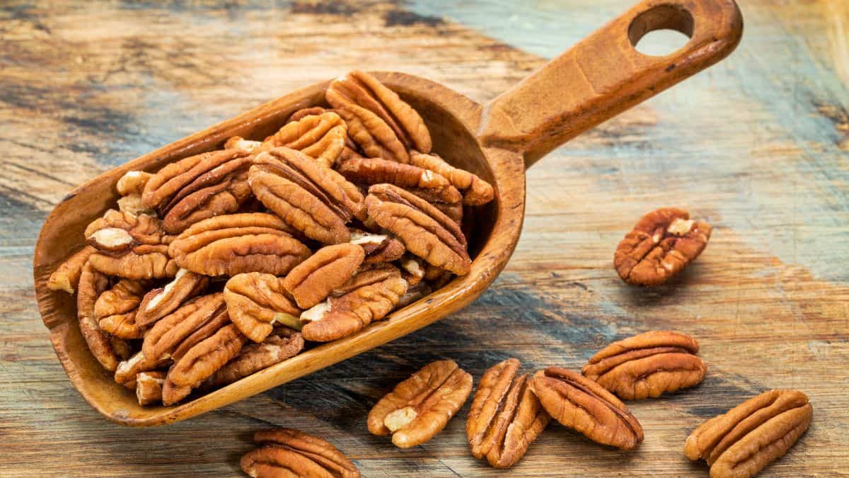 Pecans on a wooden scoop.