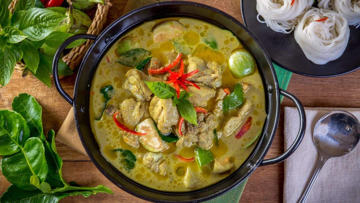 Thai green curry in a black bowl.