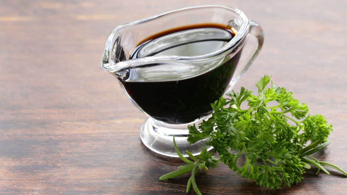 A bowl of balsamic vinegar on a brown surface.