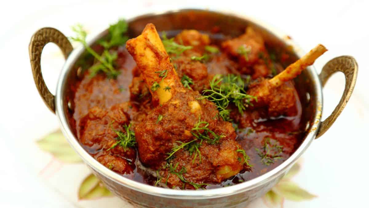 Mutton curry in a kadhai garnished with cilantro.