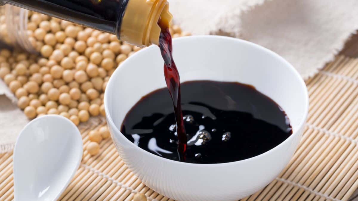 Pouring soy sauce into a white bowl.