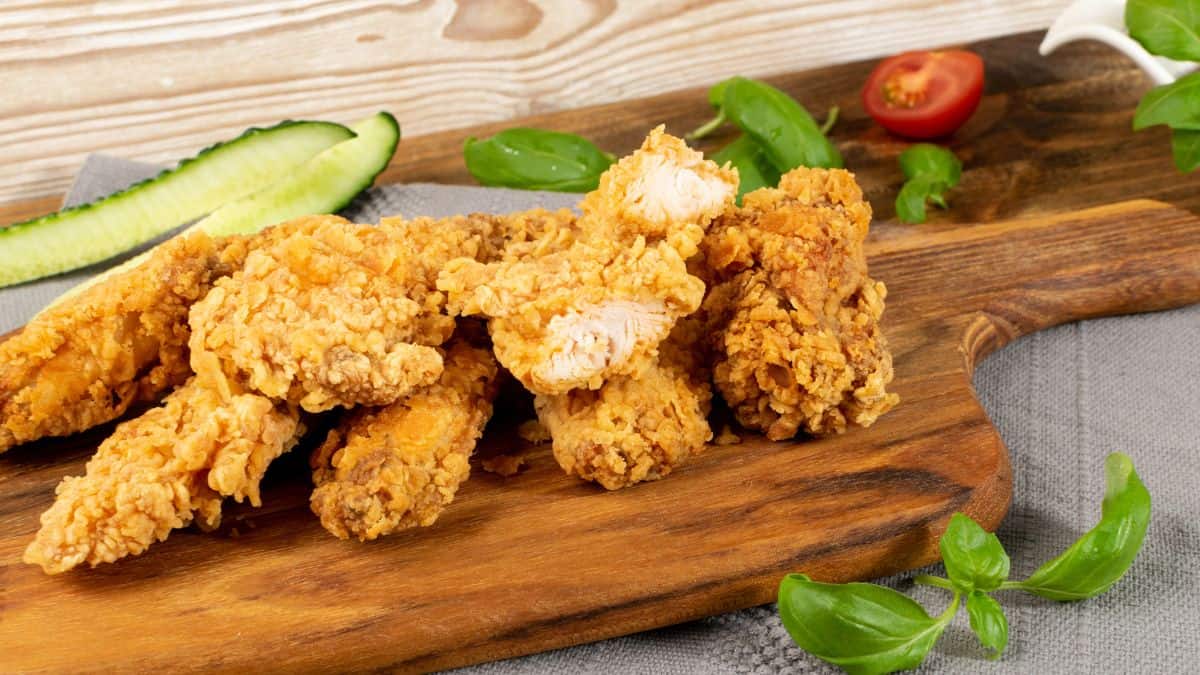 Crispy coated fish on a wooden board.