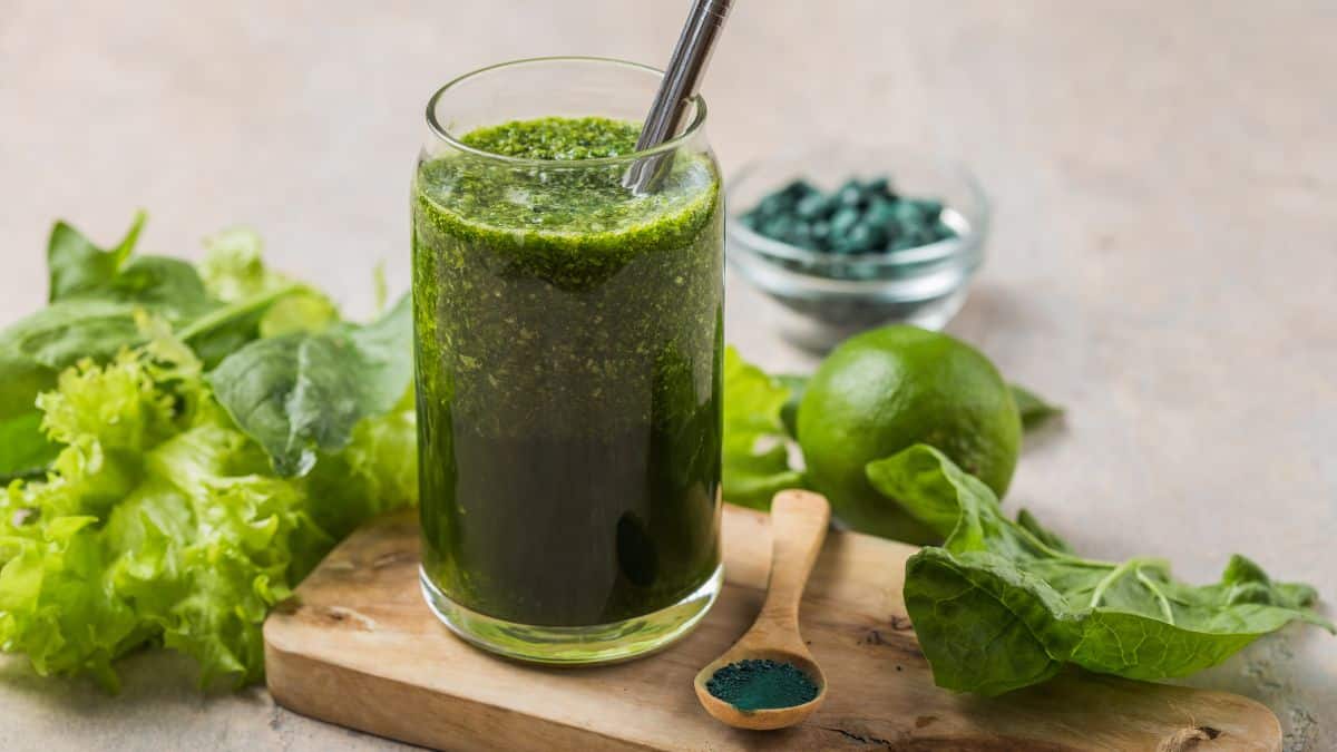 Glass of green smoothie on a wooden board.