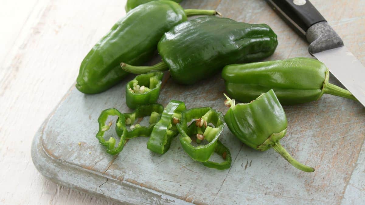 Whole and chopped jalapenos on a cutting board.