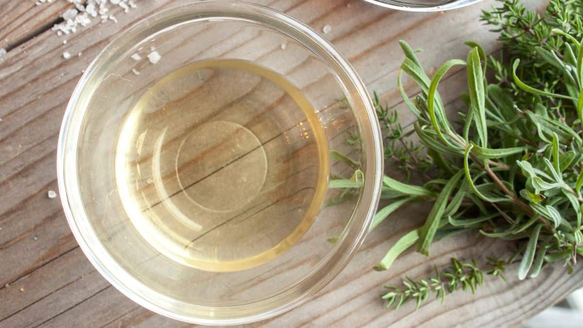 A bowl of white vinegar on a wooden surface.