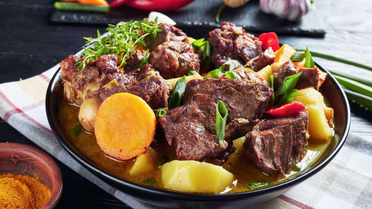 Jamaican goat curry in a black bowl.