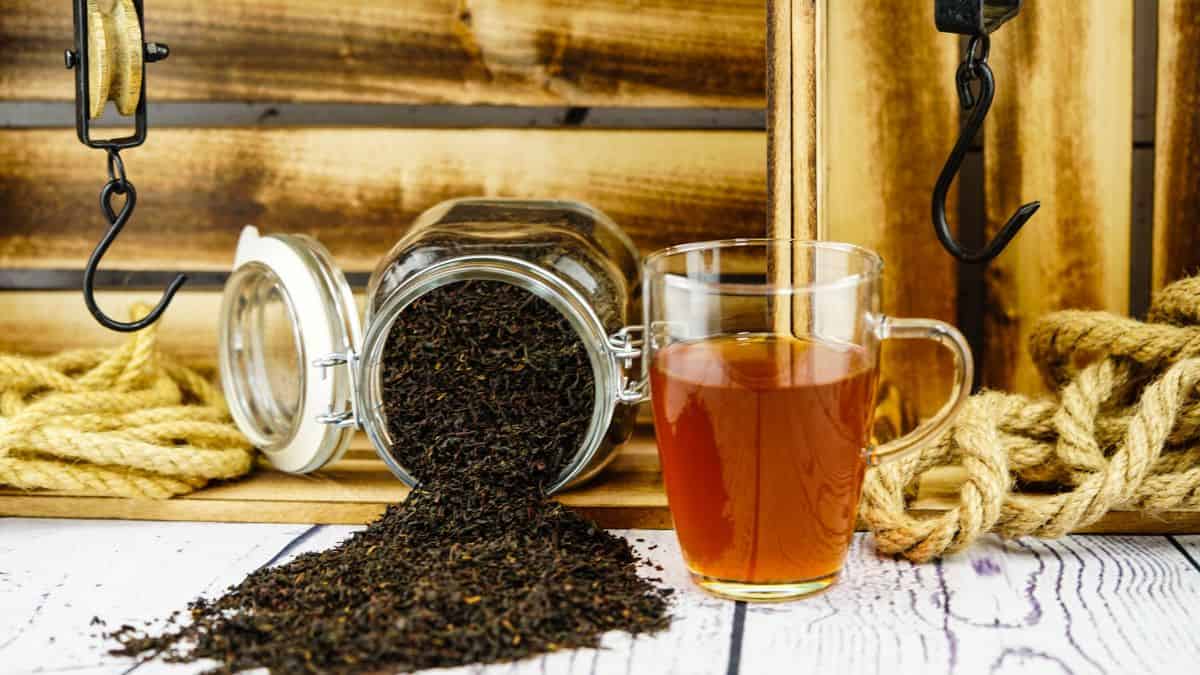 Earl grey tea in a glass cup with loose tea in the background.