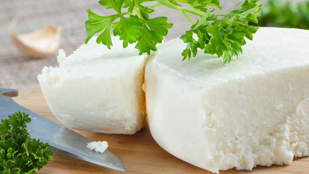 A block of cotija cheese on a wooden board.