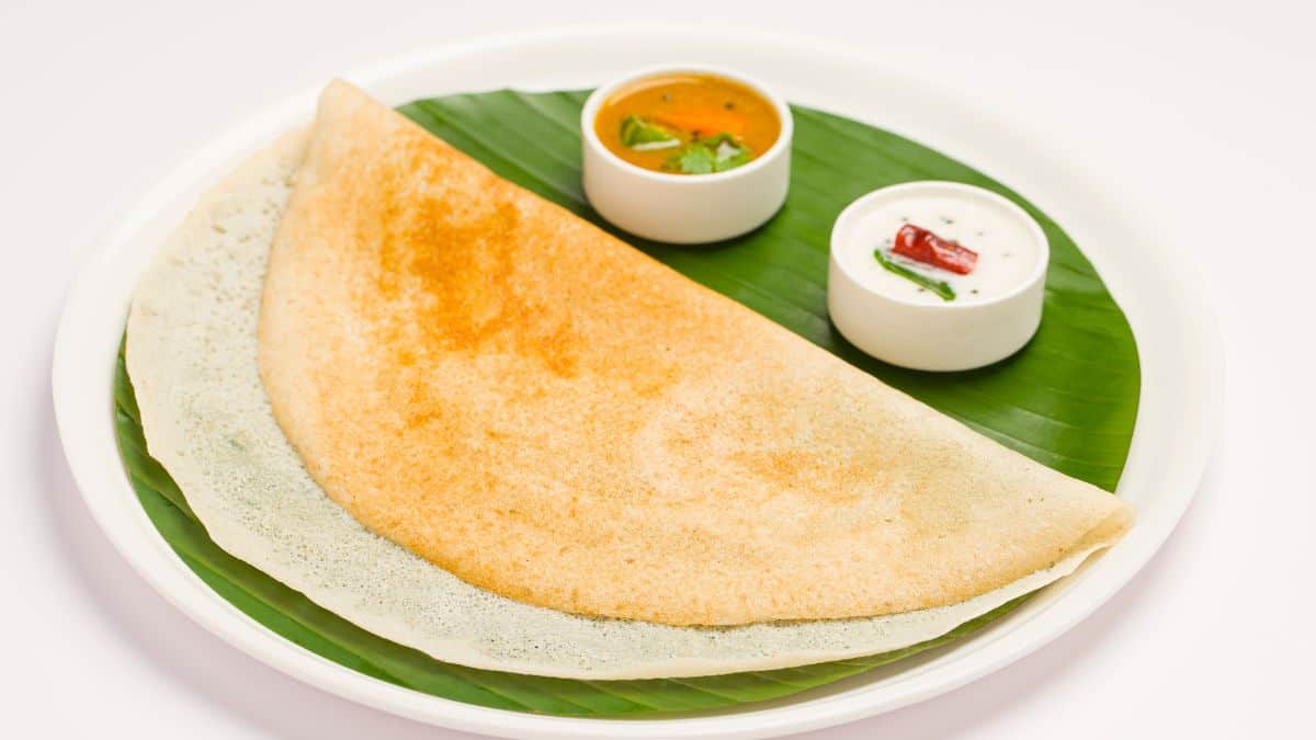 Dosa on a plate served with chutney and sambar.