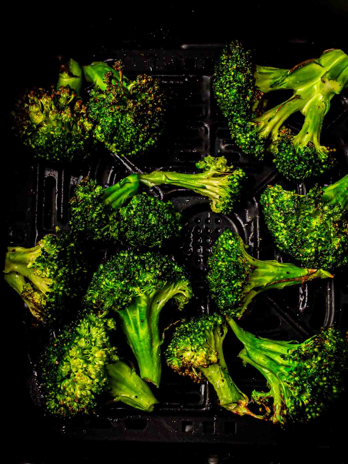 Roasted broccoli in air fryer basket.