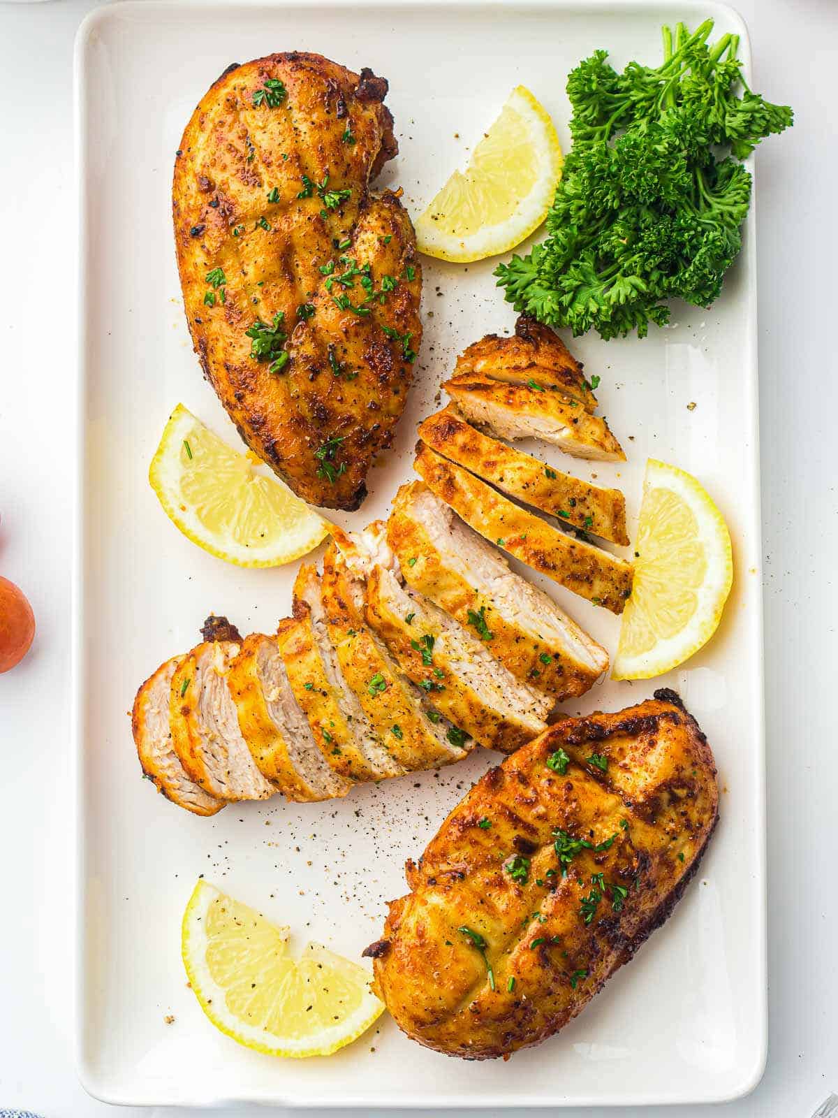 Chicken breast cooked in air fryer on a white rectangluar plate.