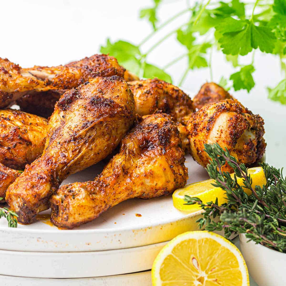 Side view of chicken drumsticks placed on a white plate.