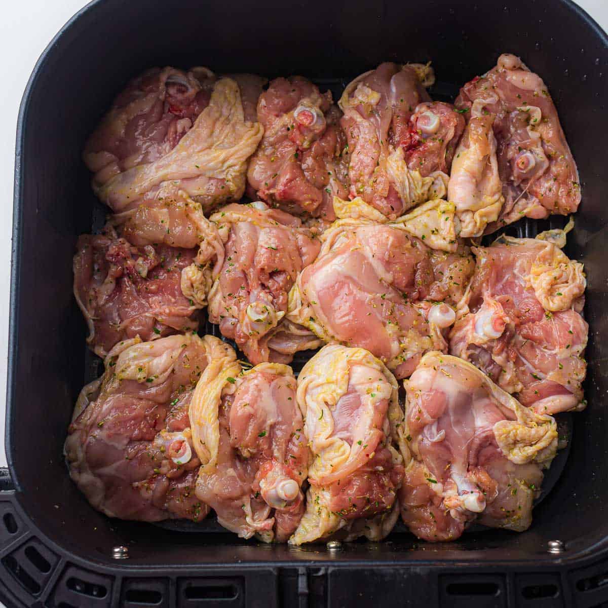 Marinated chicken in air fryer basket.