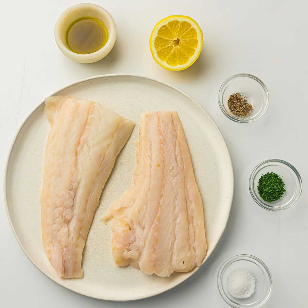 Ingredients to make air fryer cod on a white surface.