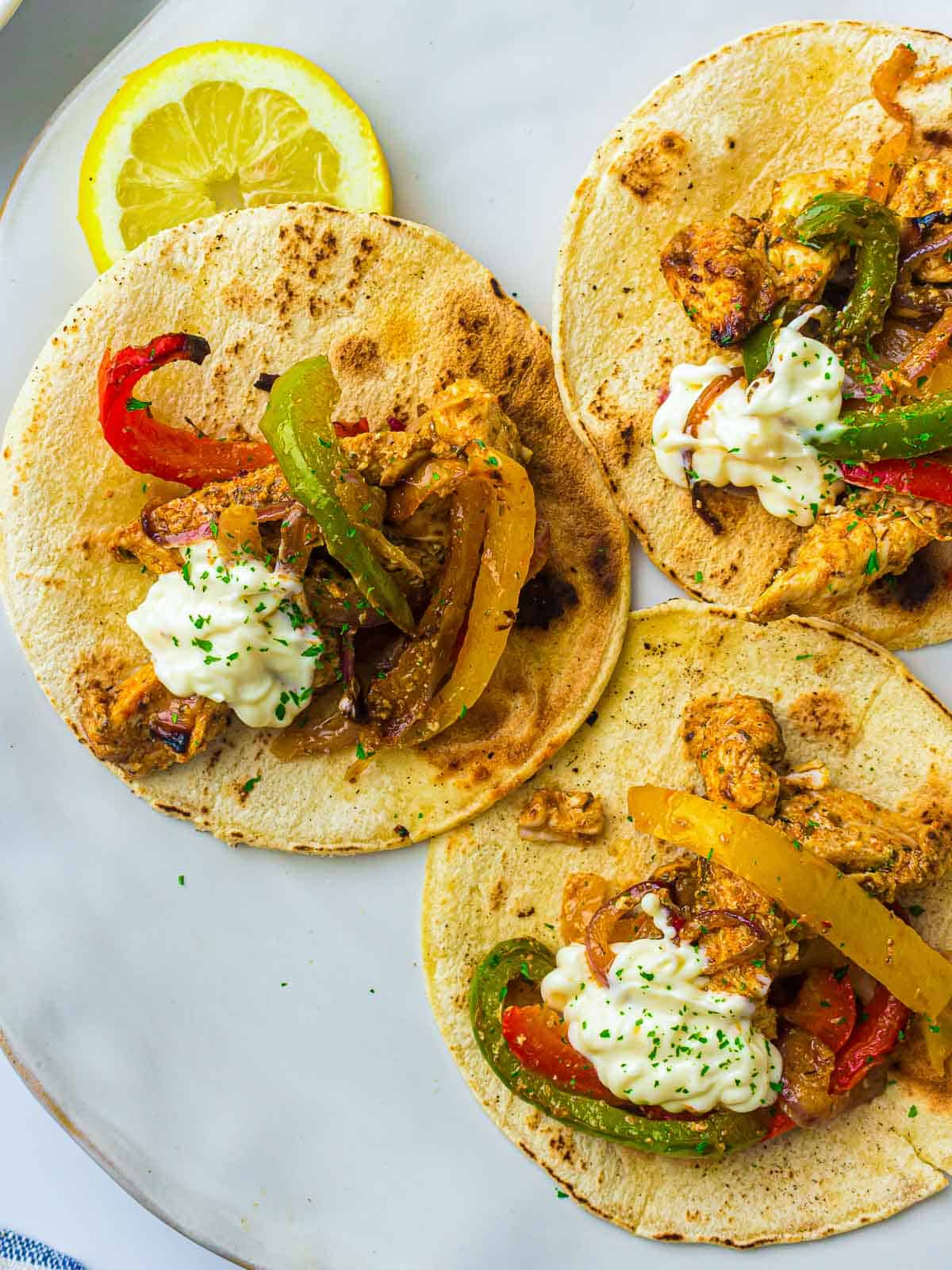 Chicken fajitas served on tortillas topped with sour cream.