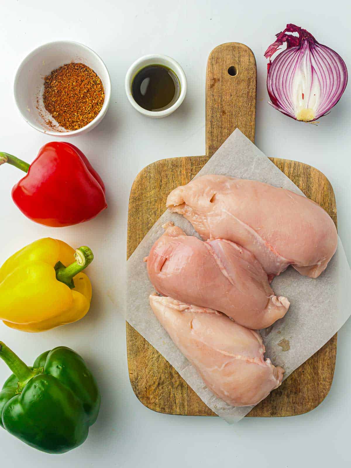 Ingredients to make chicken fajitas on a white surface.