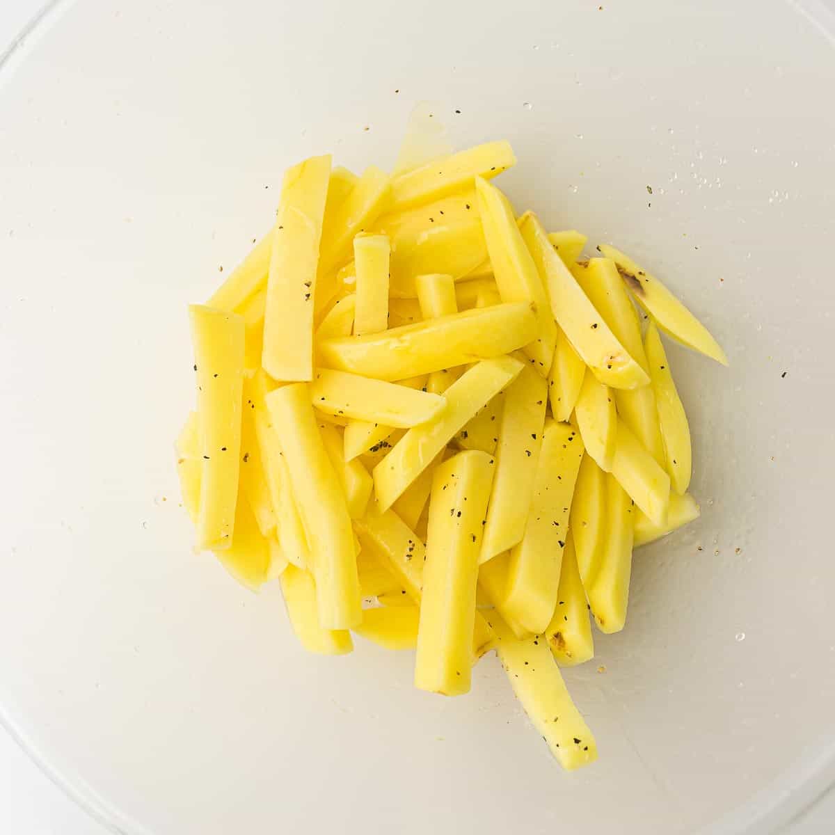 Seasoned potatoes in mixing bowl.