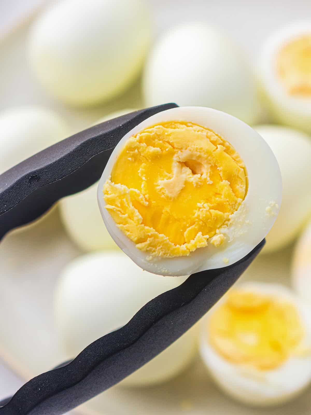 Holding perfectly boiled egg using a tong.