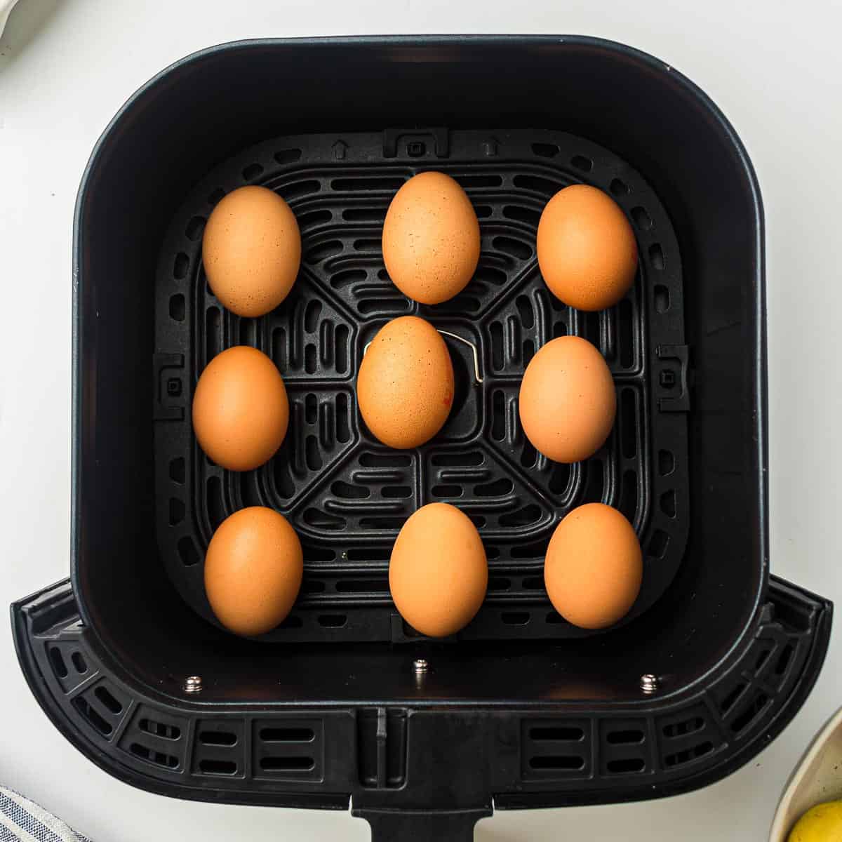 Raw eggs placed in air fryer basket.