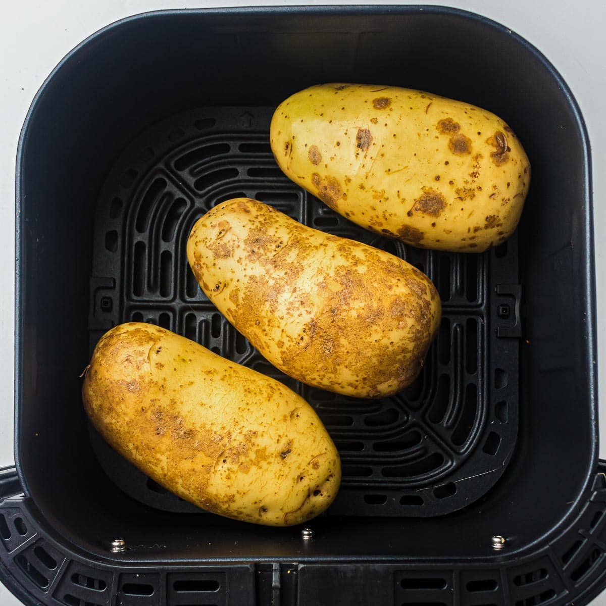 Cleaned potatoes in air fryer basket.