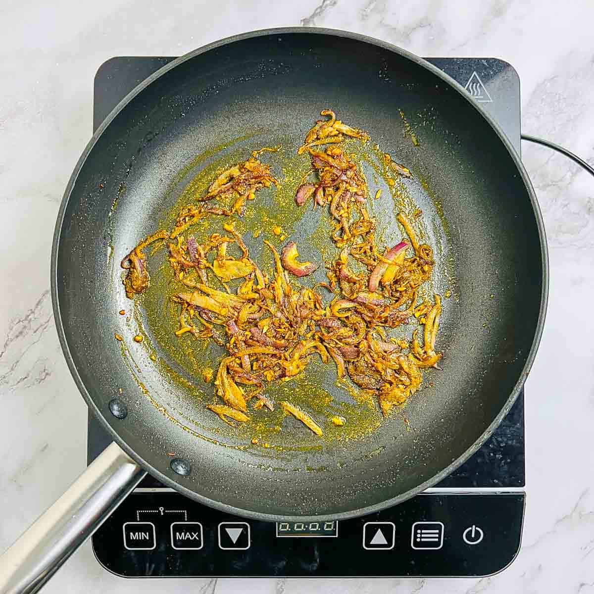 Sauted onion, garlic, and spices in the frying pan.